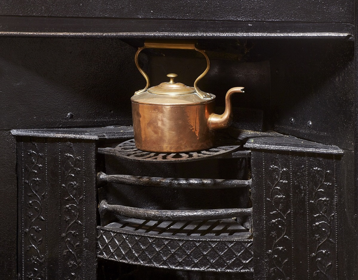 Black iron grate in the Dining Parlour at Jane Austen's House, shown with copper kettle