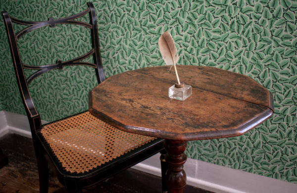 Jane Austen's writing table set against the green wallpaper in the Dining Parlour