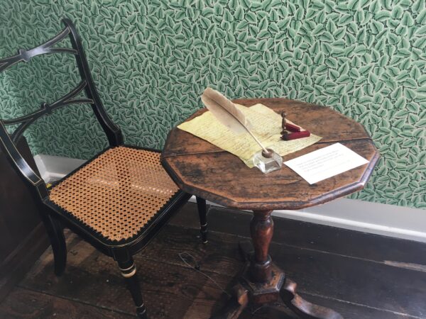 Jane Austen's small wooden writing table, with a facsimile letter and feather quill