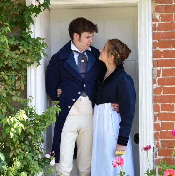 Actors portraying Captain Wentworth and Anne Ellliot from Persuasion standing in the doorway of Jane Austen's House