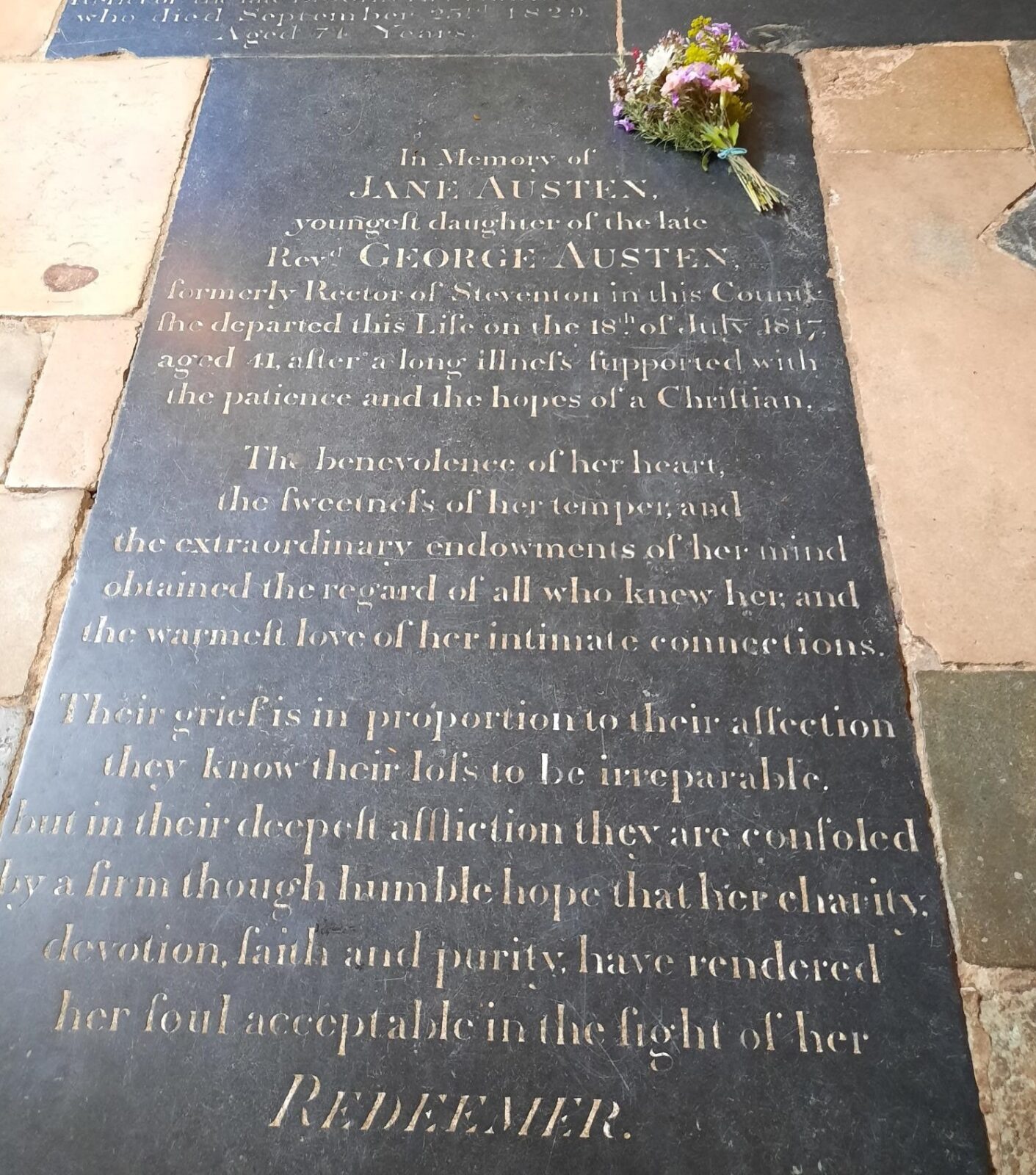 Jane Austen's gravestone in Winchester Cathedral, with a bunch of flowers laid on it