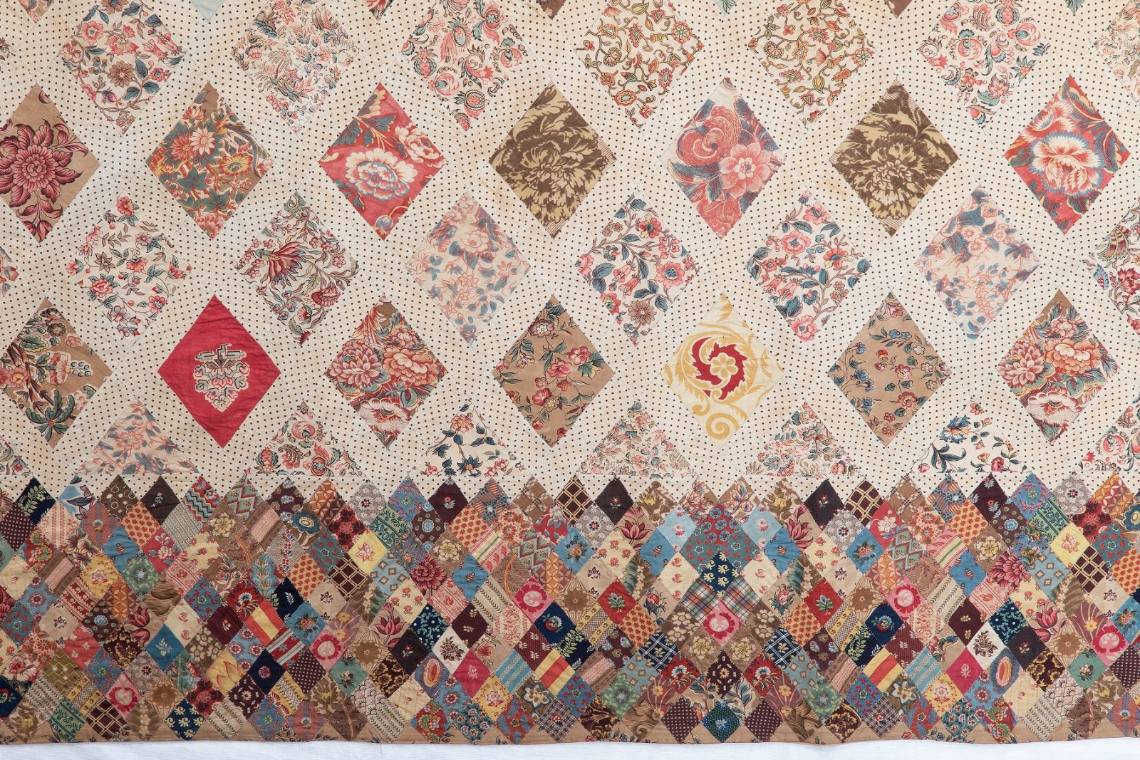 Austen family patchwork coverlet, with large diamonds in floral dress fabrics, and a border of smaller diamonds.