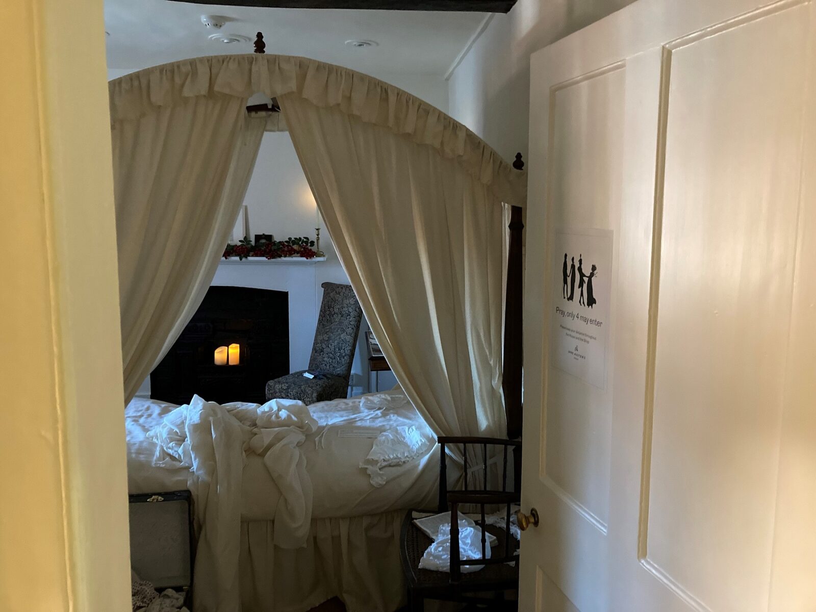 A scene from our winter exhibition, 'Six Winters': Scenes from Jane Austen's life & Imagination. This is Jane Austen's bedroom, dressed to recreate the scene of her birth with piles of washing and baby things on the bed and floor. Lit by candles and by the cold winter light from the window.
