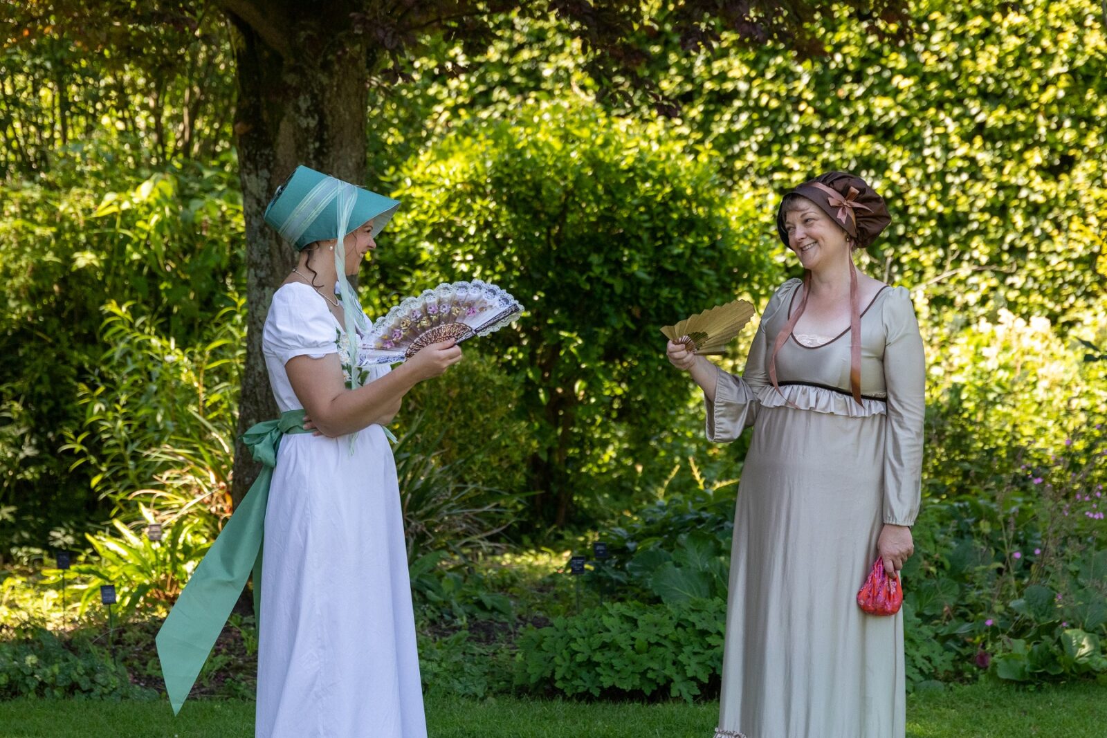 Two ladies in bonnets in the garden at Jane Austen's House