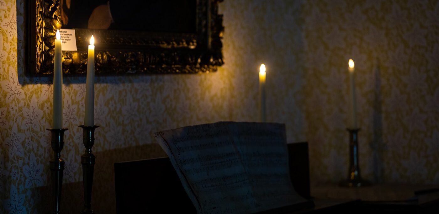Candles glow on the square piano in the Drawing Room at Jane Austen's House. Photo by Luke Shears