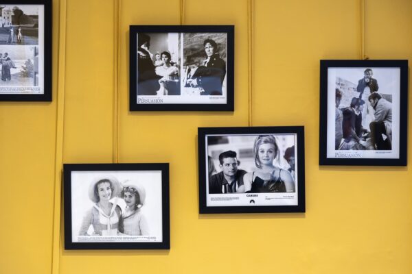 Black and white images from Jane Austen film and TV adaptations hang in black frames on a bright yellow wall.