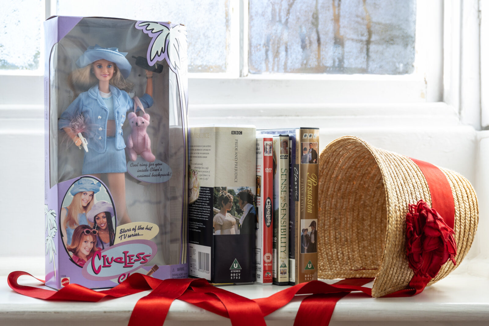 Objects from the Jane Austen's House collection representing film and TV adaptations of Jane Austen novels. Includes a doll from Clueless, DVD's from Persuasion and Sense and Sensibility and a cassette tape of Pride and Prejudice.