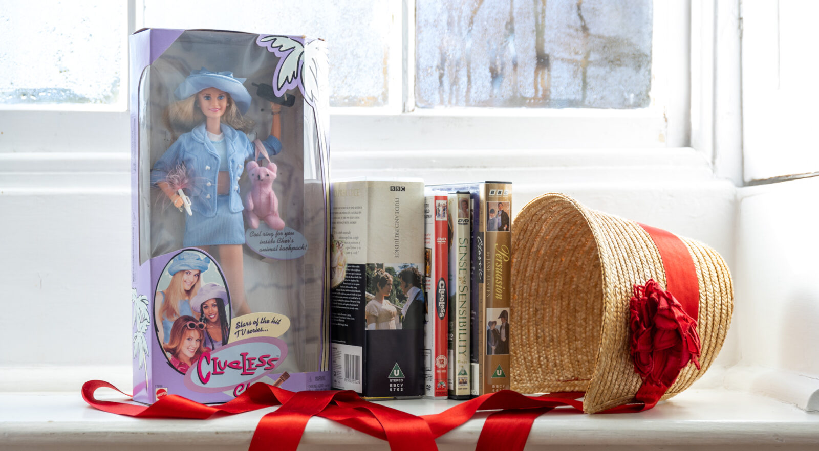 Objects from the Jane Austen's House collection representing film and TV adaptations of Jane Austen novels. Includes a doll from Clueless, DVD's from Persuasion and Sense and Sensibility and a cassette tape of Pride and Prejudice.